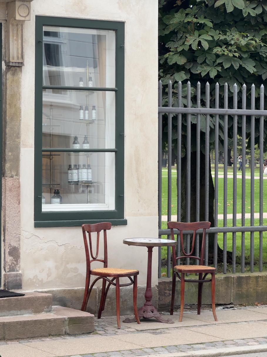 To stole og et cafébord ved et mørkegrønt vindue