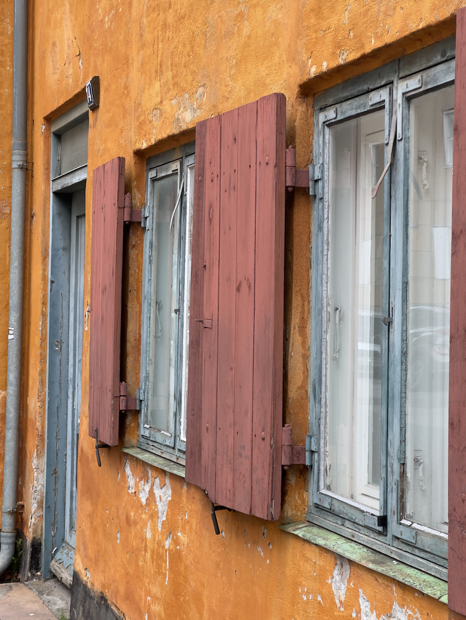Orange facade med træskodder og blågrå vinduer
